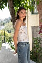 Woman wearing CALISTA crochet lace sheer corset top featuring delicate sheer crochet lace fabric, flattering scoop neckline, scalloped lace trim, lightweight layering design, soft curved hemline, and romantic boho styling for festivals, beach days, and resort getaways.