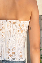 Woman wearing CALISTA crochet lace sheer corset top featuring delicate sheer crochet lace fabric, flattering scoop neckline, scalloped lace trim, lightweight layering design, soft curved hemline, and romantic boho styling for festivals, beach days, and resort getaways.