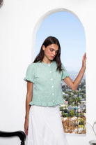 Woman wearing ELSSEE soft ruffle trim button down knit cardigan featuring soft brushed sweater knit fabric, classic crew neckline, button front closure, short puff sleeves with delicate ruffle cuffs, ruffle trim hem, and a cozy cropped silhouette for everyday layering.