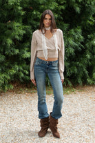 Woman wearing ADEL surplice V neck knit sweater top featuring soft marled sweater knit fabric with a cozy feel, deep V neckline, surplice wrap front design, overlapping front panels, relaxed drop shoulders, long balloon sleeves with fitted ribbed cuffs, wide ribbed waistband, slightly cropped length, and blouson fit.