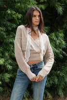 Woman wearing ADEL surplice V neck knit sweater top featuring soft marled sweater knit fabric with a cozy feel, deep V neckline, surplice wrap front design, overlapping front panels, relaxed drop shoulders, long balloon sleeves with fitted ribbed cuffs, wide ribbed waistband, slightly cropped length, and blouson fit.