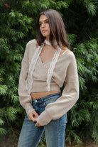 Woman wearing ADEL surplice V neck knit sweater top featuring soft marled sweater knit fabric with a cozy feel, deep V neckline, surplice wrap front design, overlapping front panels, relaxed drop shoulders, long balloon sleeves with fitted ribbed cuffs, wide ribbed waistband, slightly cropped length, and blouson fit.