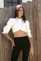 Woman wearing MAIZY eyelet trim cropped three quarter sleeve poplin blouse featuring lightweight cotton poplin fabric, romantic high ruffle neckline, delicate eyelet lace trim, open front cropped silhouette, voluminous puff sleeves, elastic ruffle cuffs, and elasticized hem for feminine styling.