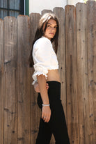 Woman wearing MAIZY eyelet trim cropped three quarter sleeve poplin blouse featuring lightweight cotton poplin fabric, romantic high ruffle neckline, delicate eyelet lace trim, open front cropped silhouette, voluminous puff sleeves, elastic ruffle cuffs, and elasticized hem for feminine styling.