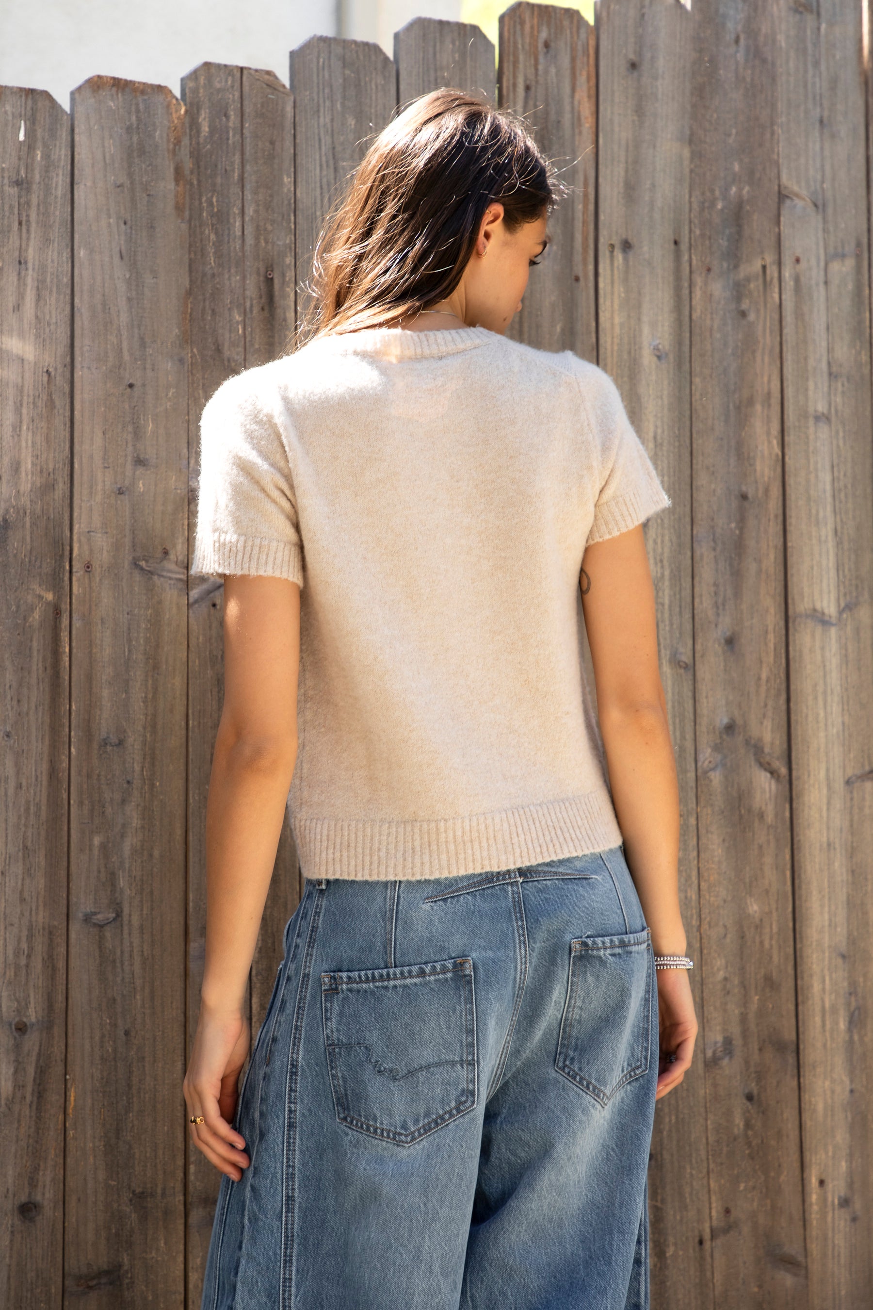 Woman wearing ADELE soft knit button short sleeve cardigan featuring plush sweater knit fabric, cozy comfortable feel, classic crew neckline, button front closure, short sleeves with ribbed cuffs and hem, and a relaxed yet flattering everyday fit for easy layering.
