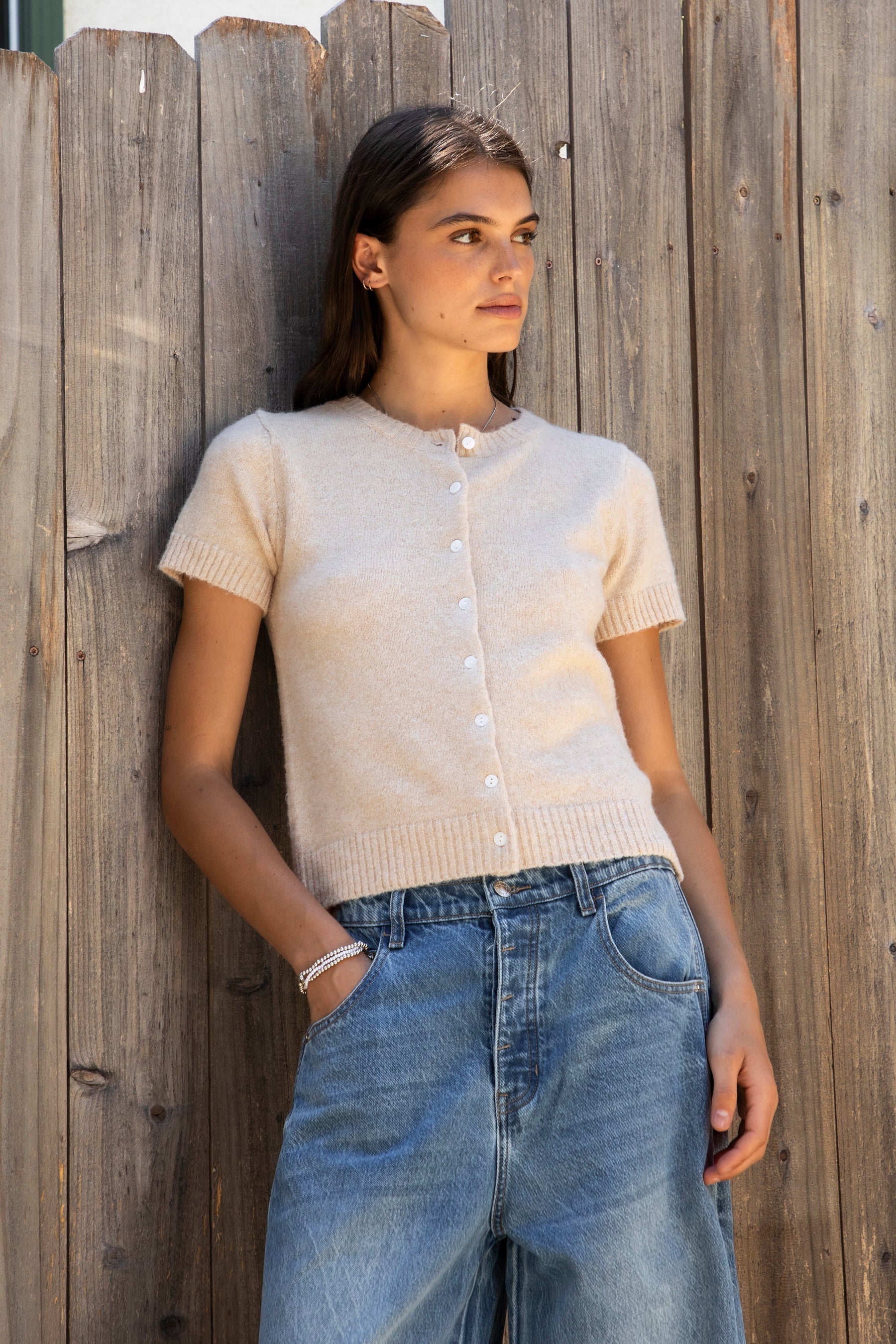 Woman wearing ADELE soft knit button short sleeve cardigan featuring plush sweater knit fabric, cozy comfortable feel, classic crew neckline, button front closure, short sleeves with ribbed cuffs and hem, and a relaxed yet flattering everyday fit for easy layering.