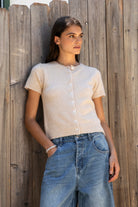 Woman wearing ADELE soft knit button short sleeve cardigan featuring plush sweater knit fabric, cozy comfortable feel, classic crew neckline, button front closure, short sleeves with ribbed cuffs and hem, and a relaxed yet flattering everyday fit for easy layering.