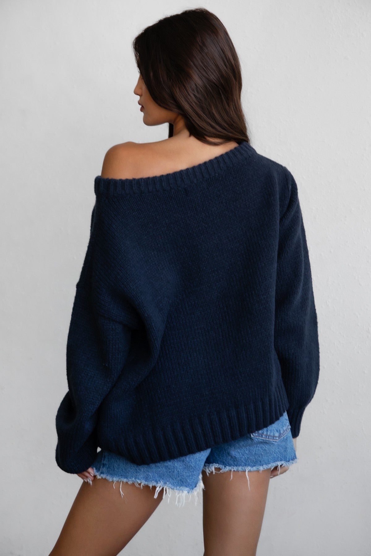 Woman wearing a TIC TOC BRANDI Ribbed Knit Sweater in navy with off-the-shoulder boat neck, American flag pattern, and semi-oversized fit with denim shorts.