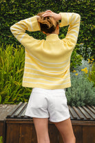 Woman wearing MAUREEN classic oversized striped half zip sweater featuring a timeless stripe pattern, half zip mock neckline with faux leather zipper pull, relaxed drop shoulder silhouette, chunky cotton sweater knit, textured rib stitching, and ribbed cuffs and hem for cozy coastal styling.