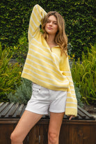 Woman wearing MAUREEN classic oversized striped half zip sweater featuring a timeless stripe pattern, half zip mock neckline with faux leather zipper pull, relaxed drop shoulder silhouette, chunky cotton sweater knit, textured rib stitching, and ribbed cuffs and hem for cozy coastal styling.