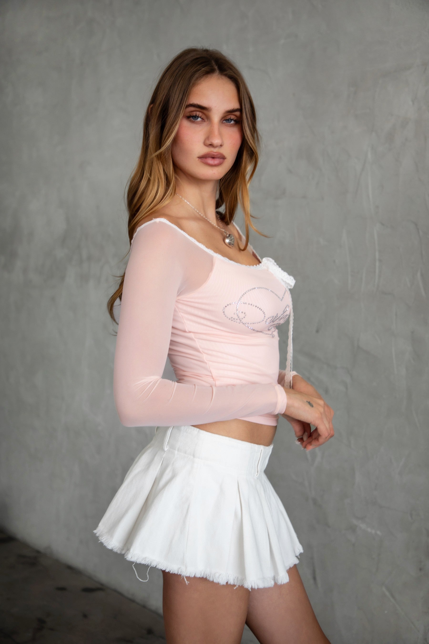 TIC TOC TC31111 ADORA Mesh Rhinestone Embellished Long Sleeve Top in pink. Features an off-the-shoulder neckline, lace trim with self-tie detail, and sparkling rhinestones.