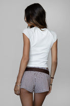 Woman wearing a white t-shirt and checkered shorts on a plain background
