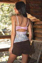 Woman showcasing Back view of CAMOURA Camo Mesh Cami Top with hook and eye closure and open back keyhole paired with brownsuede shorts. 