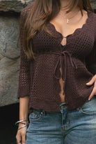 Woman wearing TC31632-ASHLYN crochet cardigan featuring a scalloped V-neckline, tie-front closure, peplum hem, and three-quarter sleeves styled as a lightweight boho western Y2K layering piece.