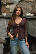 Woman wearing TC31632-ASHLYN crochet cardigan featuring a scalloped V-neckline, tie-front closure, peplum hem, and three-quarter sleeves styled as a lightweight boho western Y2K layering piece.