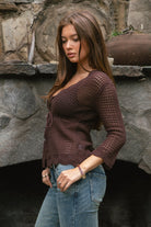 Woman wearing TC31632-ASHLYN crochet cardigan featuring a scalloped V-neckline, tie-front closure, peplum hem, and three-quarter sleeves styled as a lightweight boho western Y2K layering piece.
