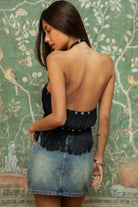 Woman wearing TIC TOC TC31634 VIXARA cropped fringe halter top featuring allover fringe tassel detailing, a flattering V-cut bust line with mesh lining, faux button detail at the halter neck, and a cropped silhouette, styled for a festival-ready western concert look.