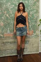 Woman wearing TIC TOC TC31634 VIXARA cropped fringe halter top featuring allover fringe tassel detailing, a flattering V-cut bust line with mesh lining, faux button detail at the halter neck, and a cropped silhouette, styled for a festival-ready western concert look.