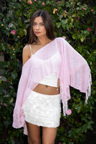 Woman wearing TIC TOC TC31650-SOLENA SOLENA crystal sequin crochet poncho featuring lightweight open crochet knit fabric, allover crystal sequin embellishments, a wide off-shoulder neckline, relaxed draped poncho silhouette, cropped asymmetrical hem, and thin tassel fringe detail, styled over a fitted inner layer for a western festival and vacation-ready look.