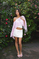 Woman wearing TIC TOC TC31650-SOLENA SOLENA crystal sequin crochet poncho featuring lightweight open crochet knit fabric, allover crystal sequin embellishments, a wide off-shoulder neckline, relaxed draped poncho silhouette, cropped asymmetrical hem, and thin tassel fringe detail, styled over a fitted inner layer for a western festival and vacation-ready look.