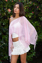 Woman wearing TIC TOC TC31650-SOLENA SOLENA crystal sequin crochet poncho featuring lightweight open crochet knit fabric, allover crystal sequin embellishments, a wide off-shoulder neckline, relaxed draped poncho silhouette, cropped asymmetrical hem, and thin tassel fringe detail, styled over a fitted inner layer for a western festival and vacation-ready look.