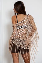 Woman wearing TIC TOC TC31690-LUNARA LUNARA sequin crochet fringe poncho featuring open crochet knit fabric, large allover sequin embellishments, a scalloped wide neckline worn off one shoulder, relaxed poncho silhouette, triangle point hem, and long fringe tassel trim, styled over a fitted top for a western festival and vacation-ready boho look.