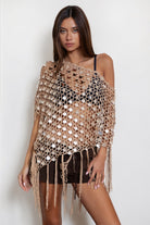 Woman wearing TIC TOC TC31690-LUNARA LUNARA sequin crochet fringe poncho featuring open crochet knit fabric, large allover sequin embellishments, a scalloped wide neckline worn off one shoulder, relaxed poncho silhouette, triangle point hem, and long fringe tassel trim, styled over a fitted top for a western festival and vacation-ready boho look.