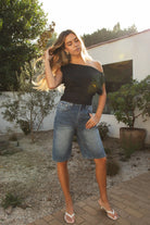 Woman wearing TIC TOC TC31874-ETOILE ETOILE asymmetrical off-the-shoulder top featuring a slash neck off-shoulder neckline, draped asymmetrical overlay front, cinched waist with ruched side detailing, and a fitted body-hugging shape in smooth stretch milk jersey, styled with high-rise bottoms for a sleek Y2K-inspired going-out look.