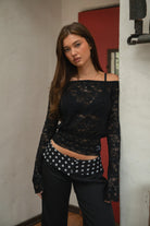 Woman wearing TC31934-VELORA floral lace off-shoulder top with bell sleeves and cropped slim fit body, styled with high-rise bottoms for a boho Y2K going-out look.