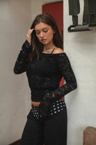 Woman wearing TC31934-VELORA floral lace off-shoulder top with bell sleeves and cropped slim fit body, styled with high-rise bottoms for a boho Y2K going-out look.