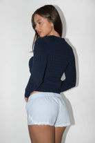 Woman wearing TIC TOC TC31963-RORYN RORYN long sleeve button-up cardigan featuring a slim fit silhouette, classic cable knit texture, collared neckline, ribbed cuffs and waistband, and a soft lightweight sweater knit feel, styled with denim for an easy everyday layered look.