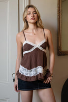 Woman wearing TIC TOC TC31970 EMMARA lace contrast polka dot babydoll cami top featuring soft peachskin fabric with a micro polka dot print, delicate lace contrast panels at the bust and hem, adjustable thin straps, a smocked back panel, and a softly draped babydoll silhouette for a romantic vintage-inspired look.