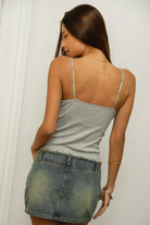 Woman wearing TIC TOC TC32064 MIA stretch jacquard jersey cropped tank top featuring a V neckline with lace trim, front tie detail at the bust, slim fitted silhouette, and cropped lettuce hem, styled with casual bottoms for a feminine Y2K-inspired summer look.