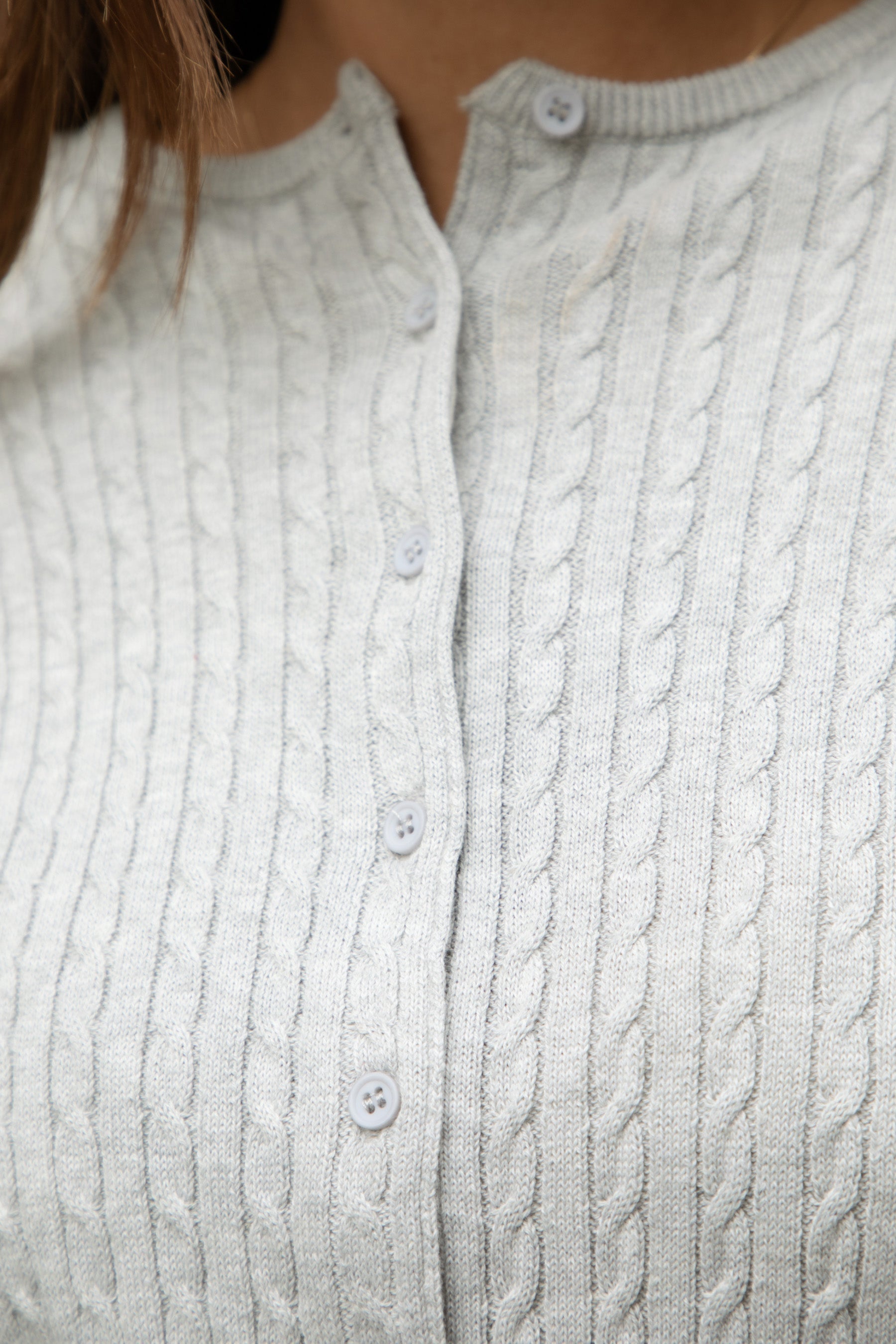 Woman wearing TIC TOC TC32069 KRISTY cable knit basic long sleeve cardigan top featuring a soft lightweight cotton cable knit texture, round neckline, full front button closure, slim fit silhouette, and semi-cropped length for a polished preppy everyday look.