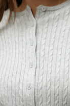 Woman wearing TIC TOC TC32069 KRISTY cable knit basic long sleeve cardigan top featuring a soft lightweight cotton cable knit texture, round neckline, full front button closure, slim fit silhouette, and semi-cropped length for a polished preppy everyday look.