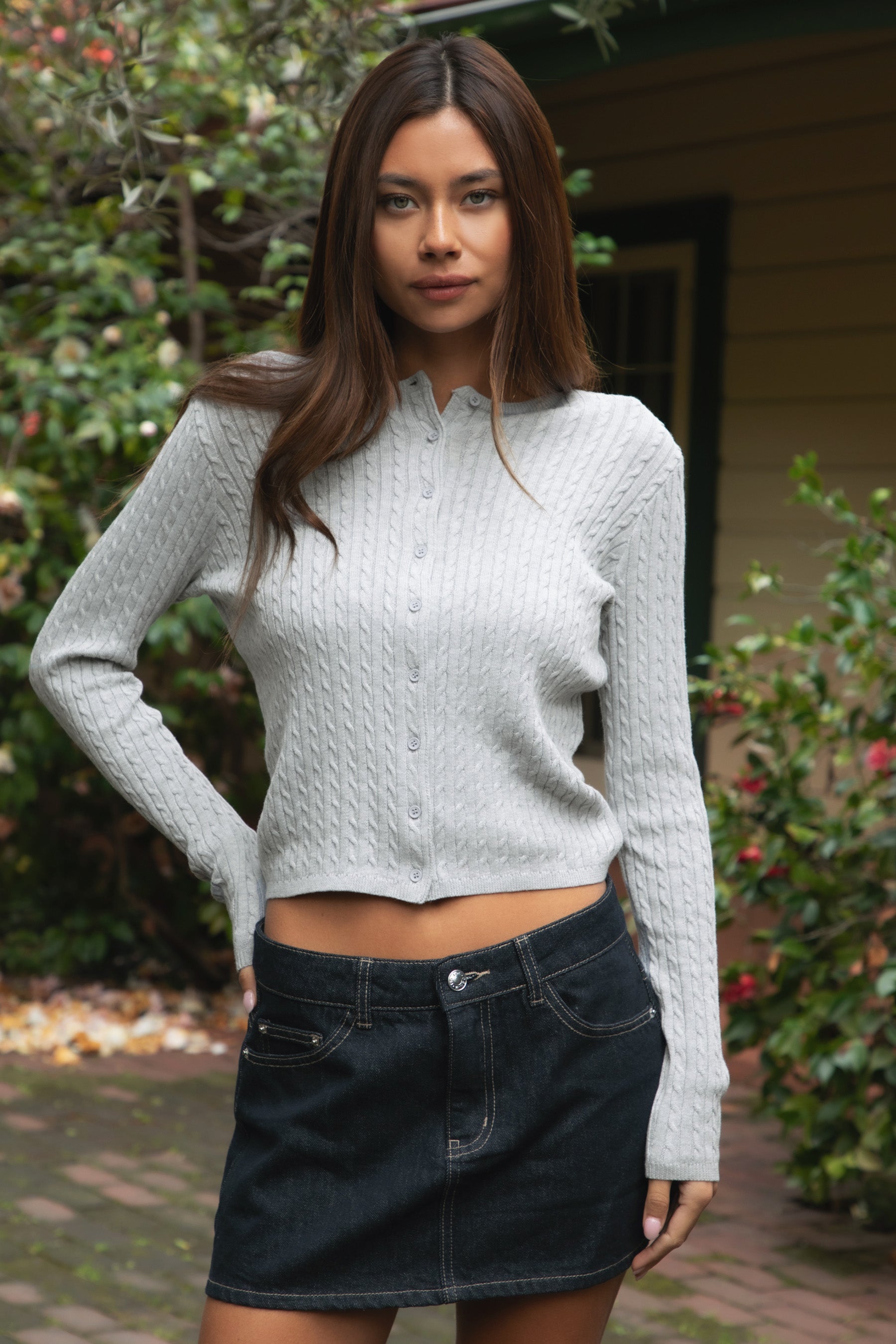 Woman wearing TIC TOC TC32069 KRISTY cable knit basic long sleeve cardigan top featuring a soft lightweight cotton cable knit texture, round neckline, full front button closure, slim fit silhouette, and semi-cropped length for a polished preppy everyday look.