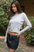 Woman wearing TIC TOC TC32069 KRISTY cable knit basic long sleeve cardigan top featuring a soft lightweight cotton cable knit texture, round neckline, full front button closure, slim fit silhouette, and semi-cropped length for a polished preppy everyday look.