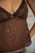 Woman wearing TIC TOC TC32070 CHLOE chiffon sequin babydoll cami top featuring sheer chiffon fabric with sequin and bead embroidery, a flattering V-neckline with picot lace trim, adjustable spaghetti straps, a delicate bow at the bust, and a cropped babydoll silhouette for a feminine going-out look.