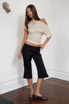 Woman wearing TIC TOC TC32074-AURE AURE striped slash neck ruched waist top featuring soft stretch jersey fabric with a contrast brown pinstripe pattern, wide slash neckline styled off one shoulder, fitted ruched waist detail, short sleeves, and a cropped hem, paired with high-rise denim for a Y2K casual, trendy street look.