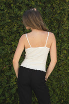 Woman wearing LOTTIE polka dot print lace contrast jersey tank featuring a delicate polka dot print, V-neckline with self-tie bow detail, lace trim along the neckline and under bust, adjustable thin straps, and a soft stretch jersey body-skimming silhouette.