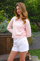 Woman wearing LUMEE rolled neck long sleeve knit sweater featuring a minimal rolled neckline, soft cotton knit fabric, long sleeves with ribbed cuffs and hem, center back seam detail, and a relaxed cropped fit for easy everyday layering.