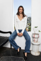 Woman wearing CAMILLE cable knit basic babydoll sweater top featuring soft cable knit texture, comfortable stretch feel, flattering deep V neckline, relaxed babydoll silhouette, long sleeves with ribbed cuffs and hem, and cozy sweater knit construction for everyday fall styling.