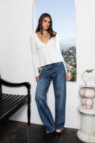 Woman wearing CAMILLE cable knit basic babydoll sweater top featuring soft cable knit texture, comfortable stretch feel, flattering deep V neckline, relaxed babydoll silhouette, long sleeves with ribbed cuffs and hem, and cozy sweater knit construction for everyday fall styling.