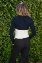 Woman wearing ARDEN V-neck long sleeve cable knit bolero cardigan featuring a classic cable knit design, cropped bolero silhouette, three-button front closure, ribbed cuffs and hem, and soft cotton knit fabric for comfortable everyday layering.