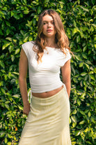 Woman wearing SELENE boat neck cowl back side tie crop top featuring an elegant boat neckline, draped cowl back, adjustable back strap, side tie ruching details, cap short sleeves, and lightweight stretch jersey fabric for a feminine cropped silhouette.