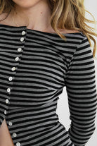 Woman wearing VELA stripe jersey long sleeve cardigan featuring a classic stripe pattern, boat neckline, front button closure, long sleeves, and soft stretch jersey fabric designed to pair with coordinating VELA micro shorts for cozy lounge and casual styling.