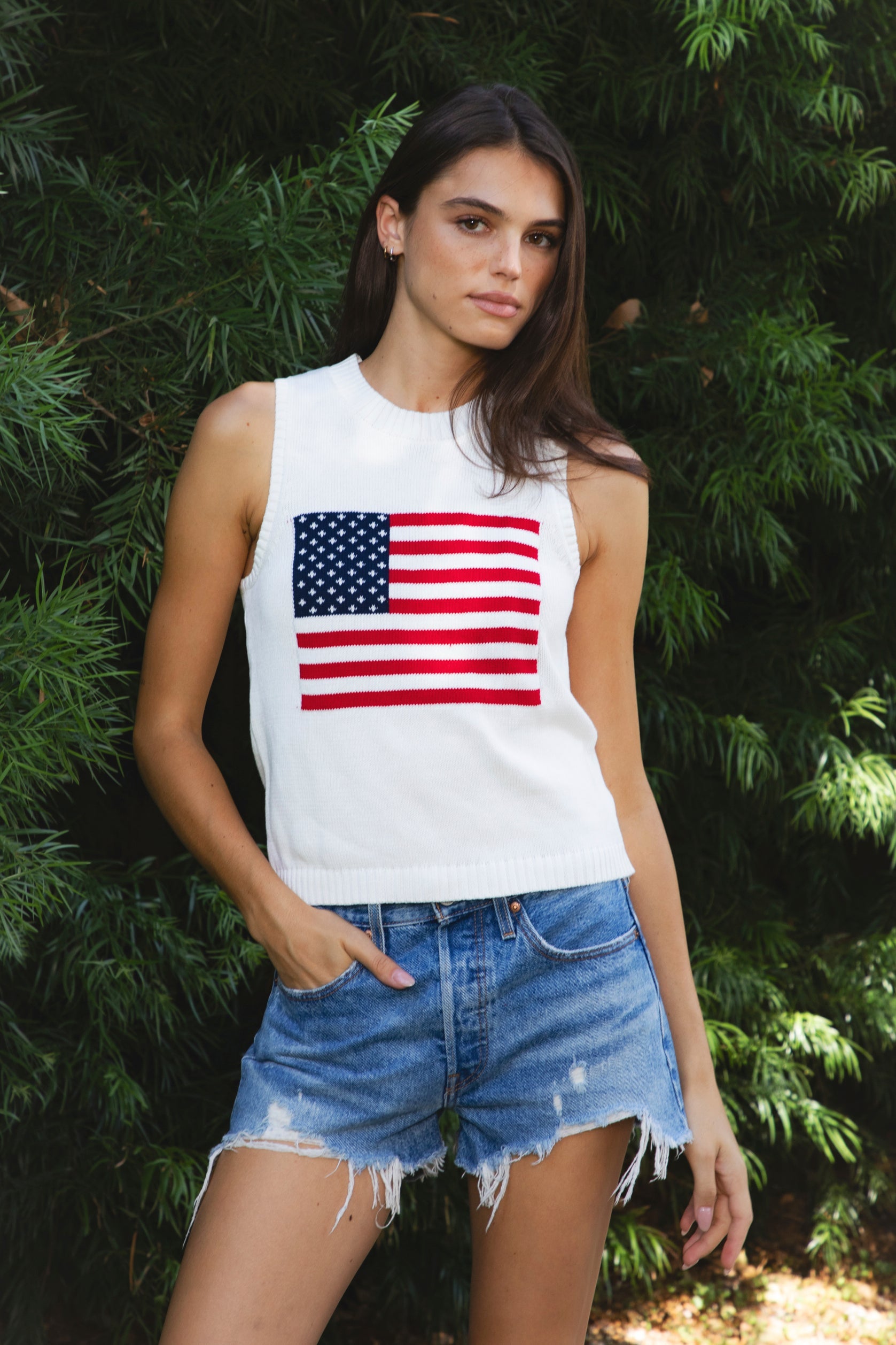 Woman wearing LIBBY American flag sweater knit tank featuring soft breathable 100% cotton sweater knit fabric, clean fitted silhouette, classic crew neckline, sleeveless design, American flag knit graphic across the front, ribbed trim along the neckline and armholes, and ribbed hem for a structured finish.