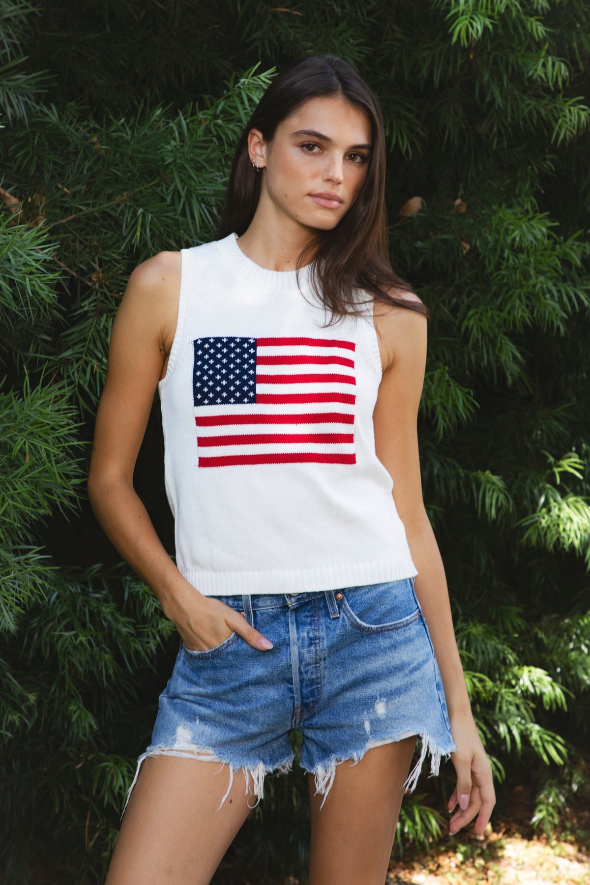 Woman wearing LIBBY American flag sweater knit tank featuring soft breathable 100% cotton sweater knit fabric, clean fitted silhouette, classic crew neckline, sleeveless design, American flag knit graphic across the front, ribbed trim along the neckline and armholes, and ribbed hem for a structured finish.