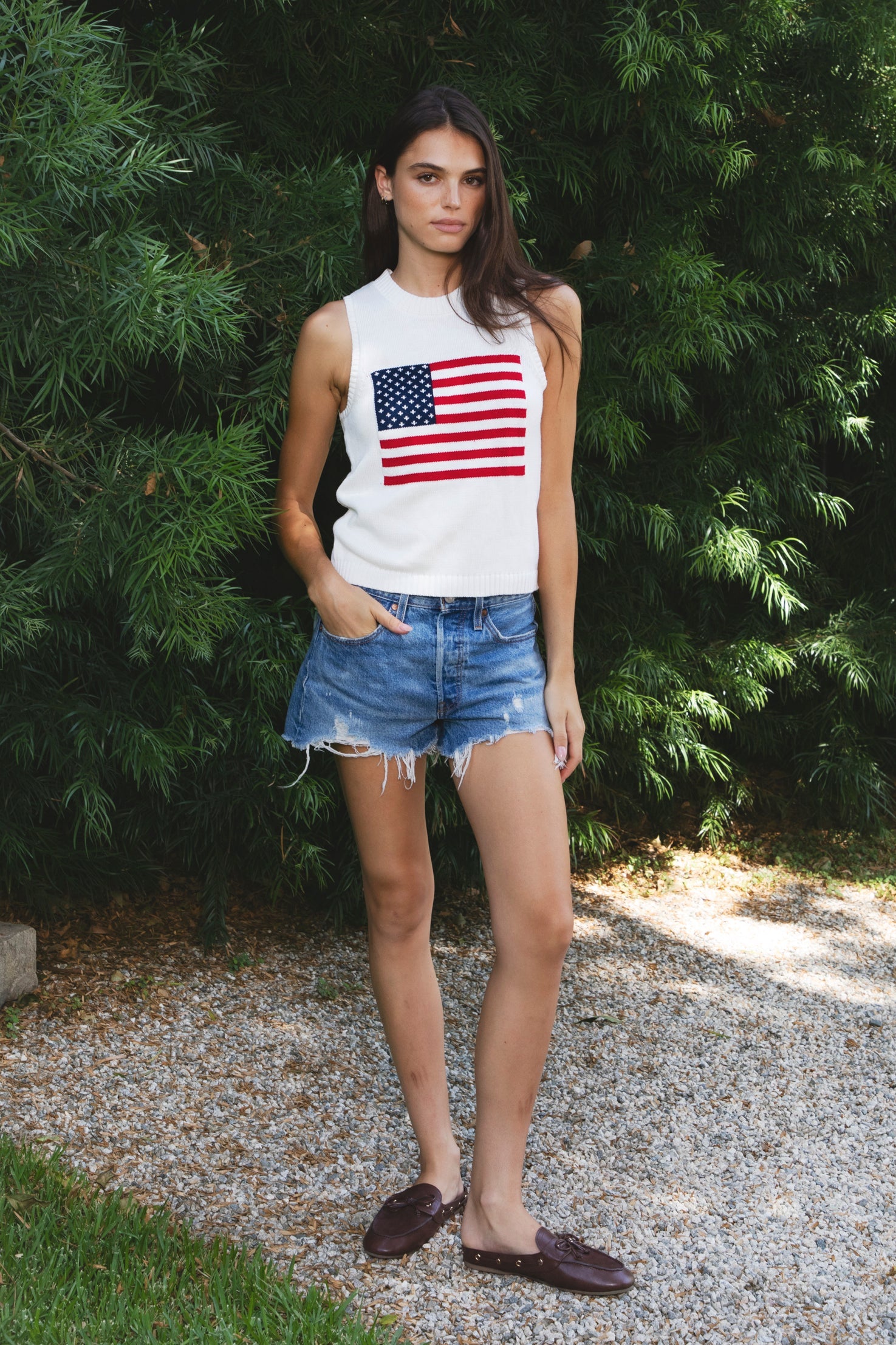 Woman wearing LIBBY American flag sweater knit tank featuring soft breathable 100% cotton sweater knit fabric, clean fitted silhouette, classic crew neckline, sleeveless design, American flag knit graphic across the front, ribbed trim along the neckline and armholes, and ribbed hem for a structured finish.