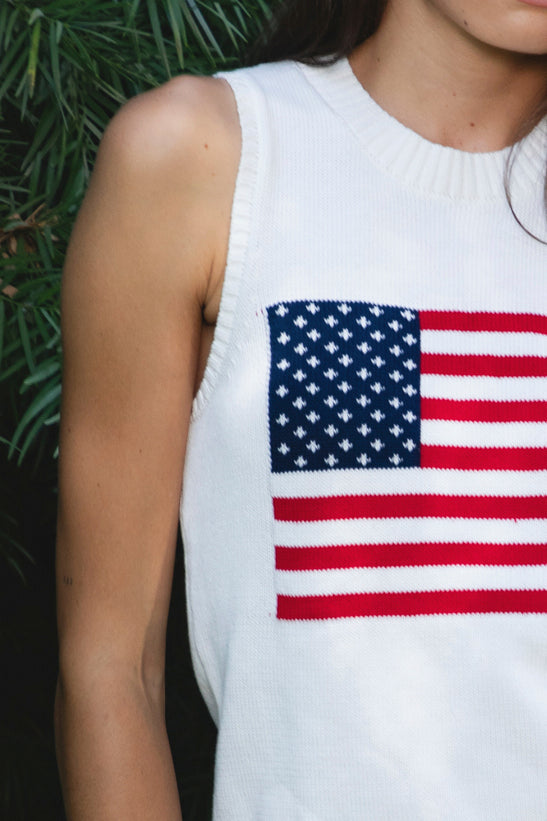 Woman wearing LIBBY American flag sweater knit tank featuring soft breathable 100% cotton sweater knit fabric, clean fitted silhouette, classic crew neckline, sleeveless design, American flag knit graphic across the front, ribbed trim along the neckline and armholes, and ribbed hem for a structured finish.